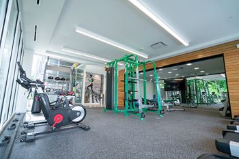 A gym with a variety of equipment including a stationary bike and a leg press machine.